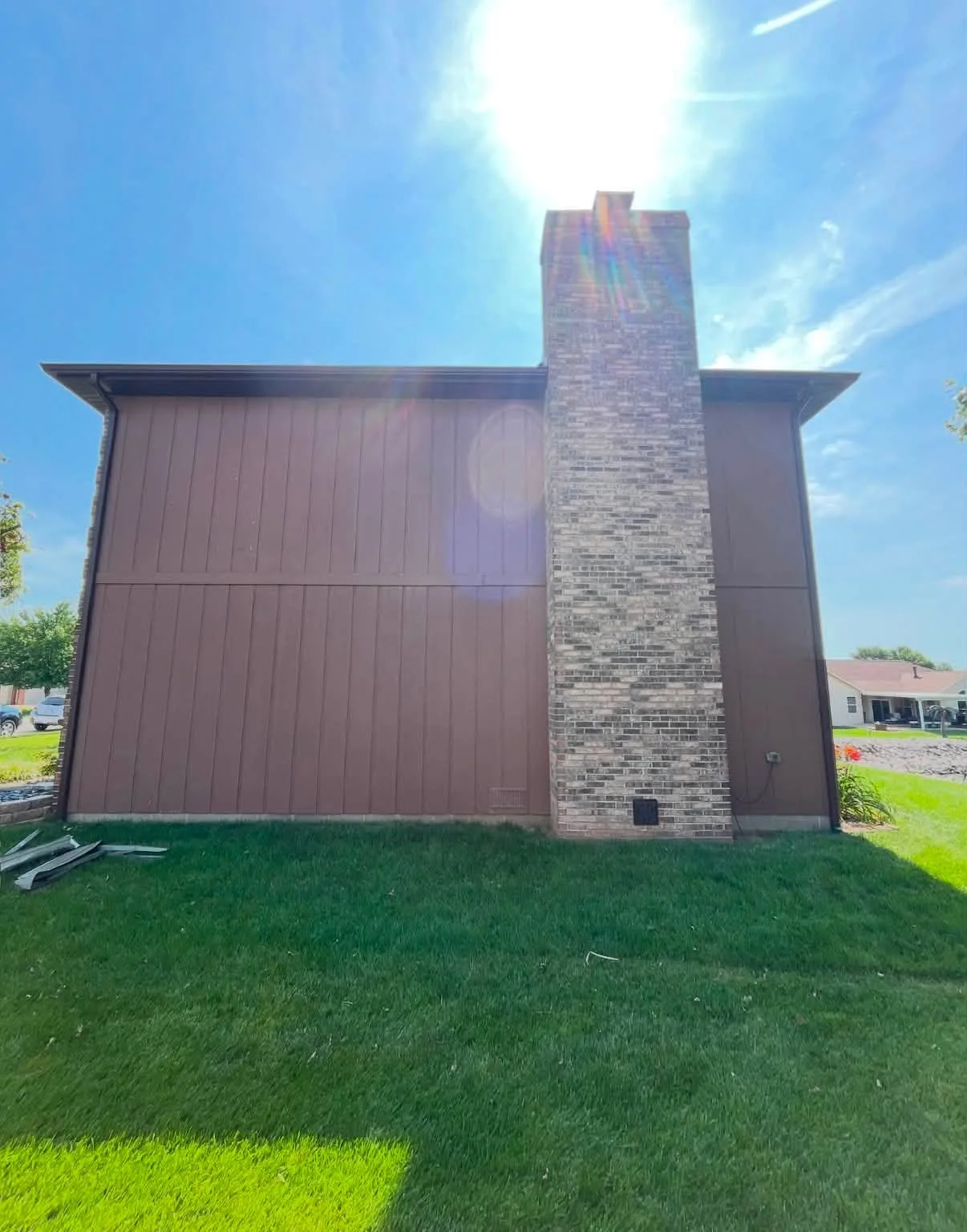Finished brown siding and white trim beside the brick chimney